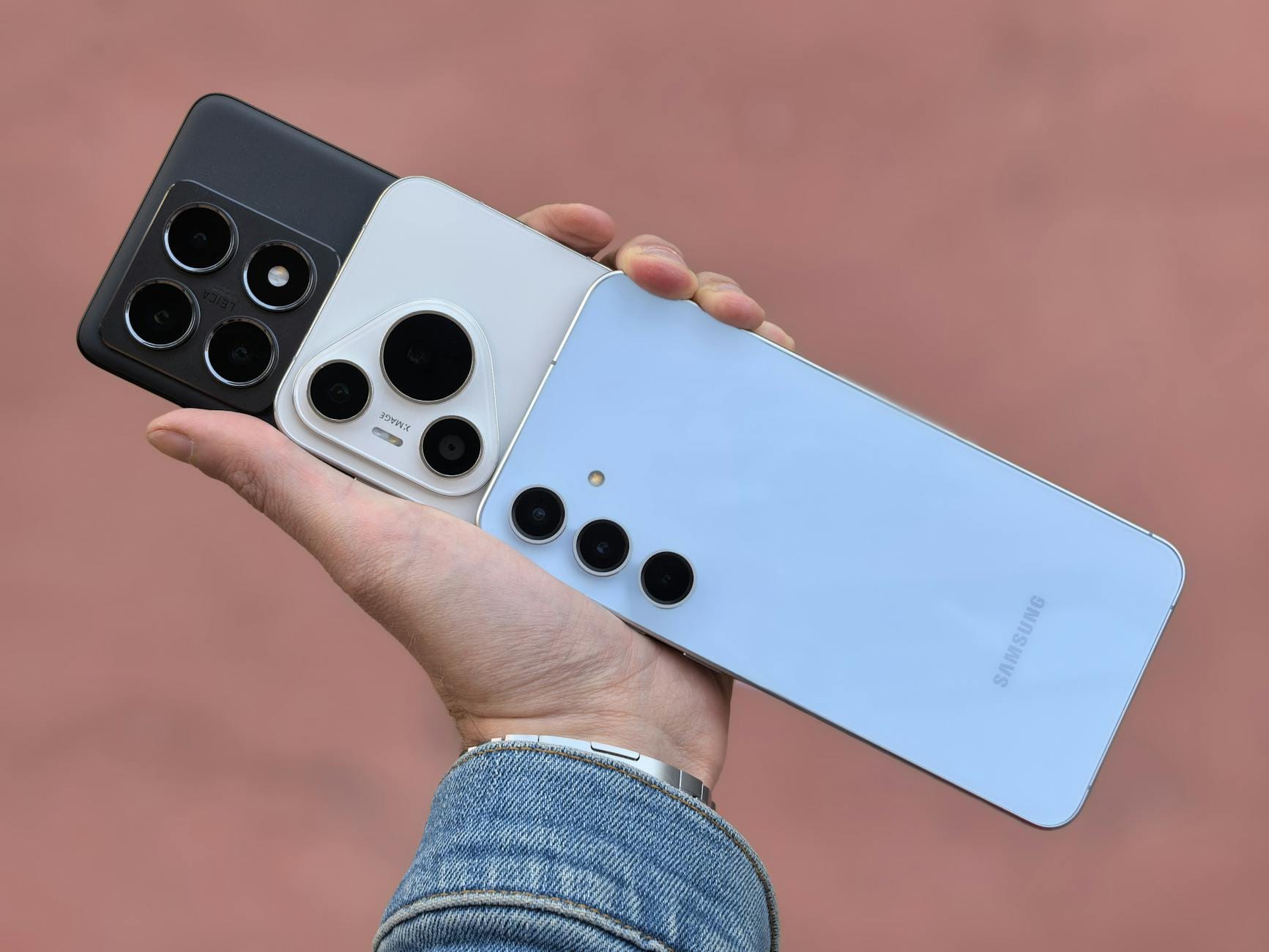 Dłoń trzymająca trzy smartfony z różnymi aparatami na obudowie