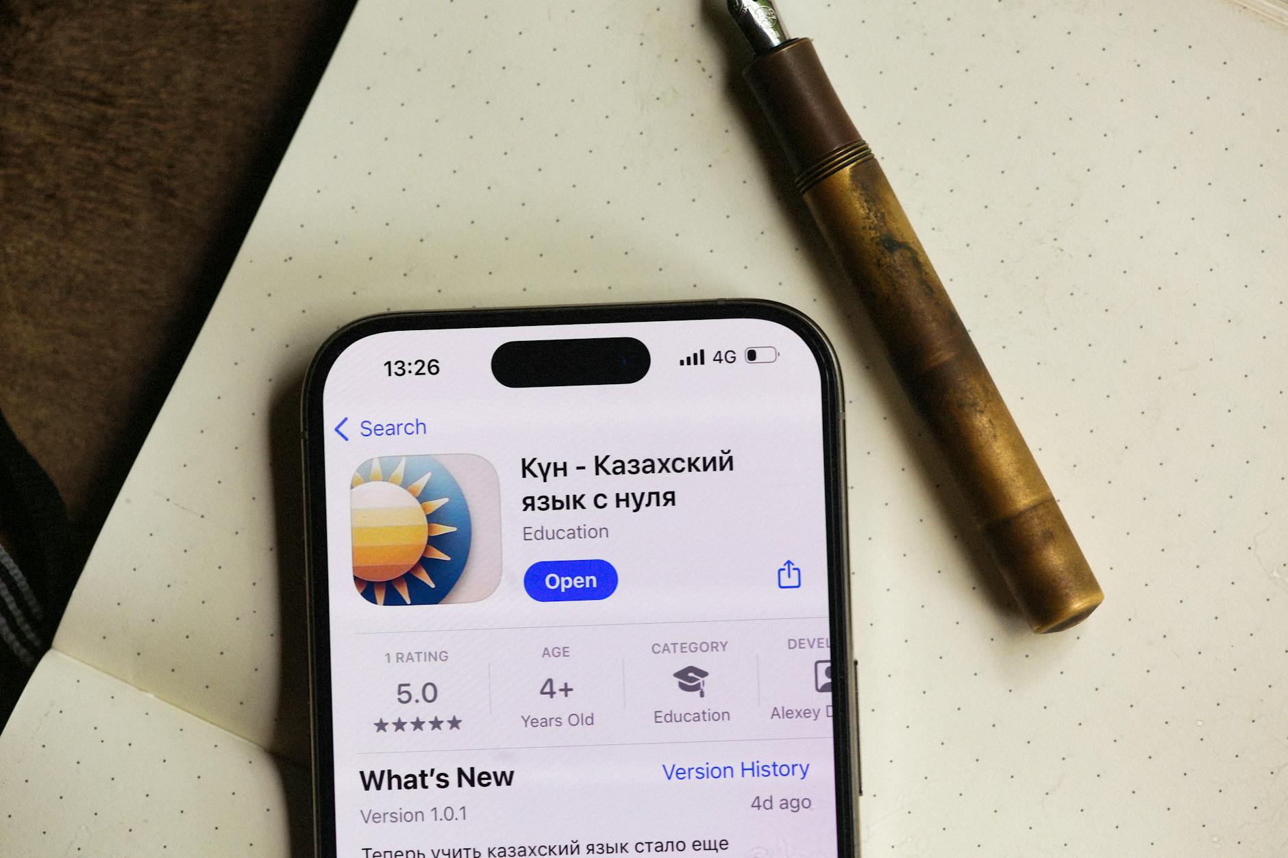 Smartfon z aplikacją edukacyjną obok długopisu na kropkowanym notesie
