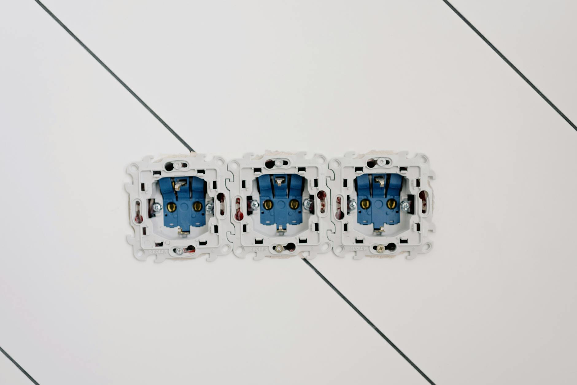 Gniazdka elektryczne i śruby montażowe na ścianie w mieszkaniu