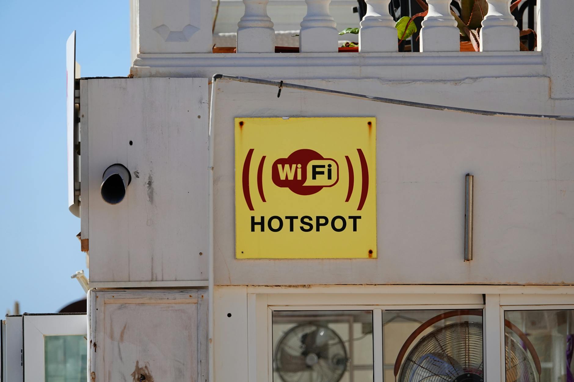 Żółty szyld z napisem WiFi Hotspot na elewacji budynku