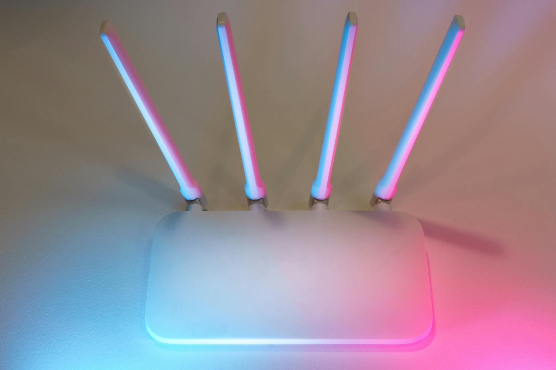 Biały router Wi‑Fi z czterema antenami i świecącymi diodami LED