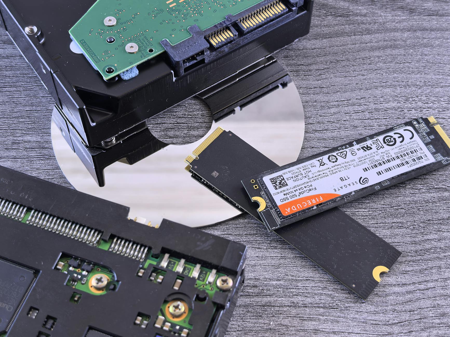 Dysk NVMe SSD, dysk HDD i płyta CD obok siebie na biurku