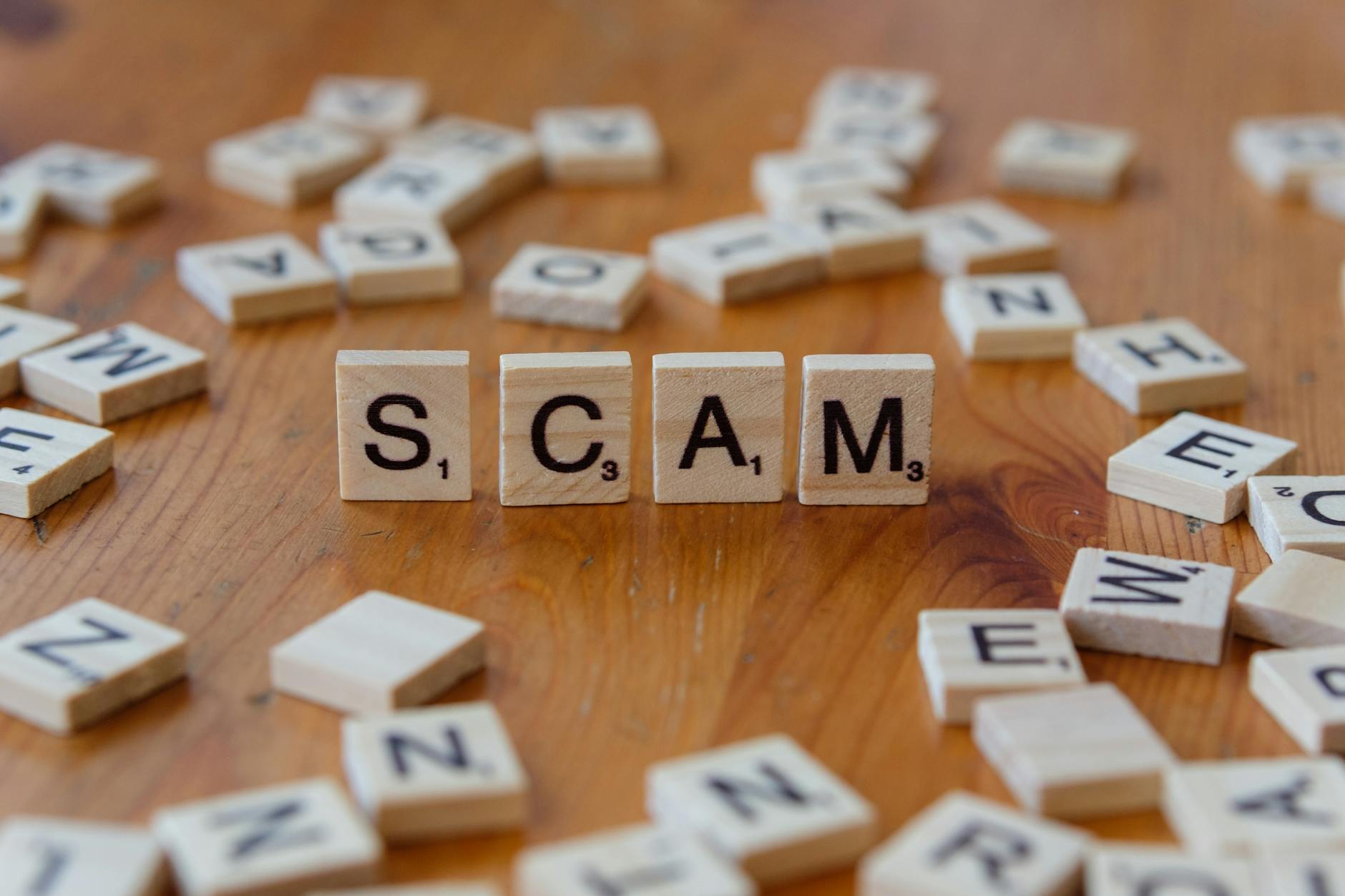 Klocki Scrabble układające się w słowo scam na drewnianym stole