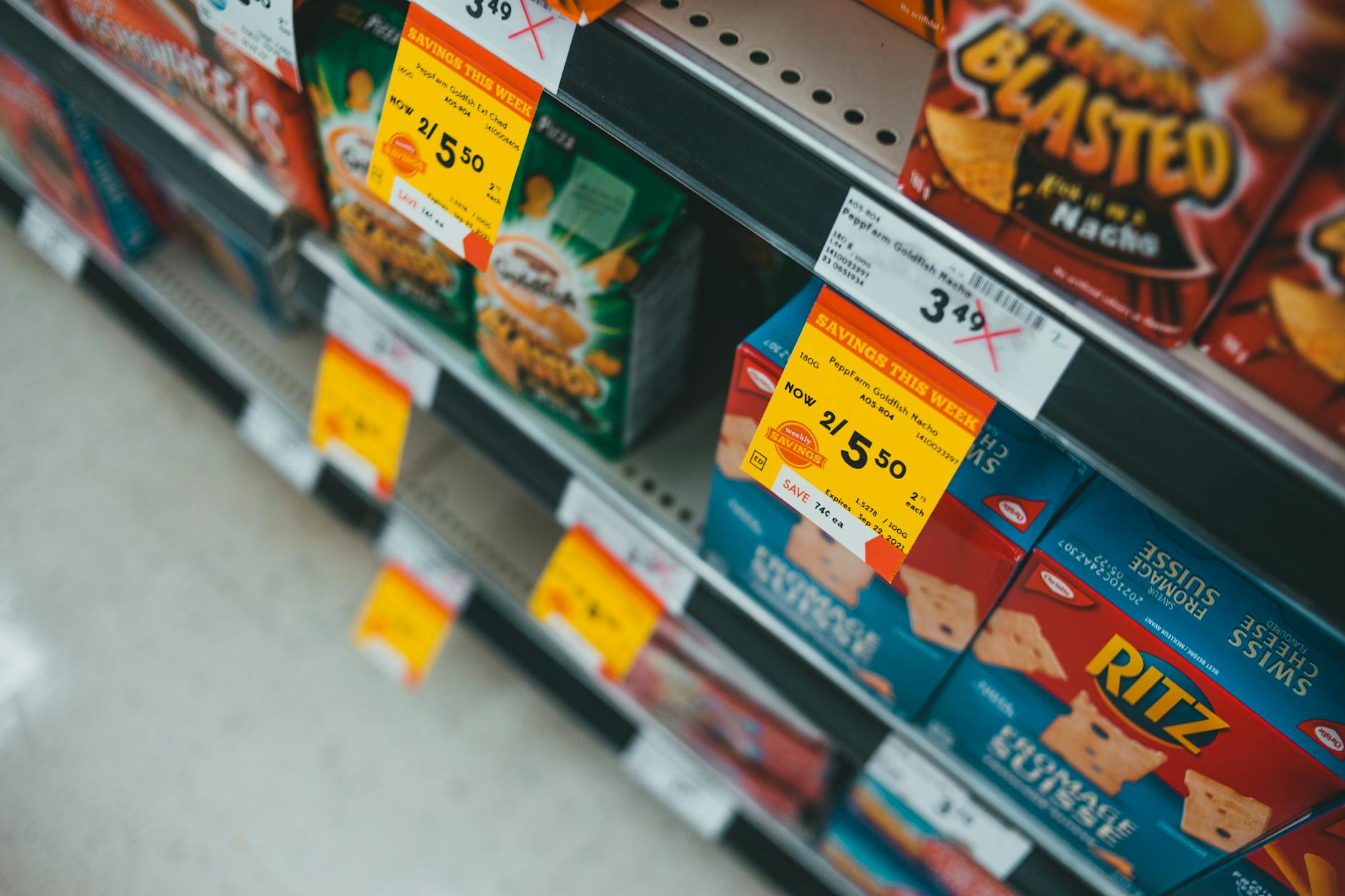 Półka w supermarkecie z przecenionymi przekąskami i żółtymi cenówkami