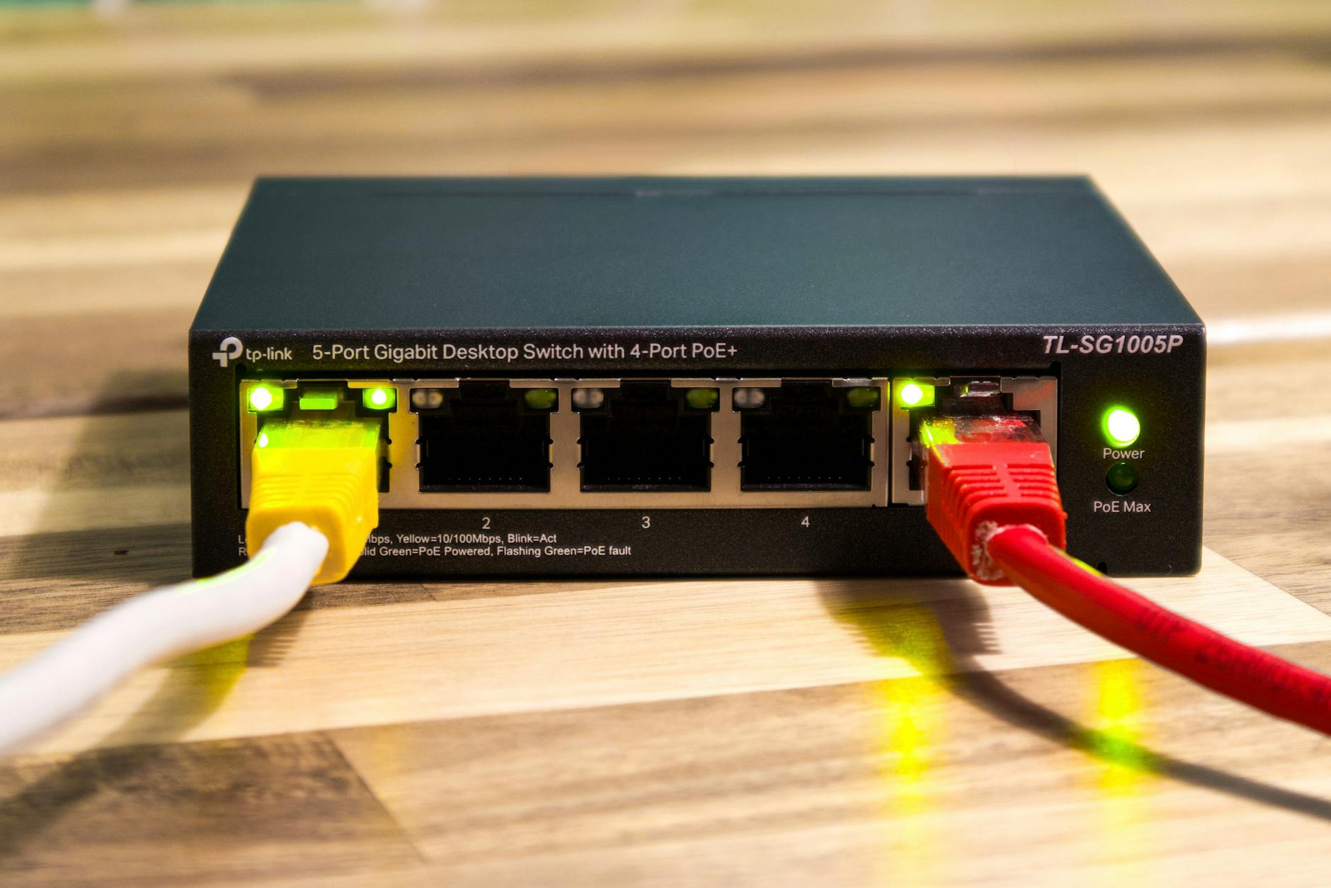 Przełącznik TP-Link z podłączonymi żółtymi, czerwonymi i białymi kablami