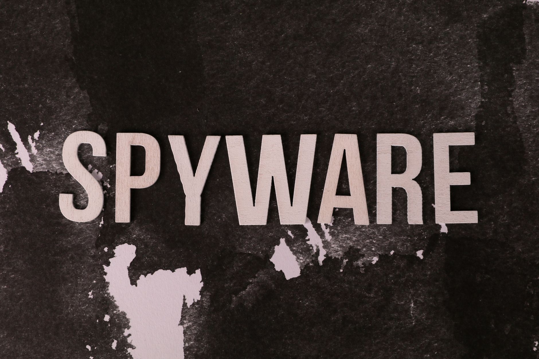 Czarno-biały napis spyware na chropowatym tle nawiązujący do szpiegowania
