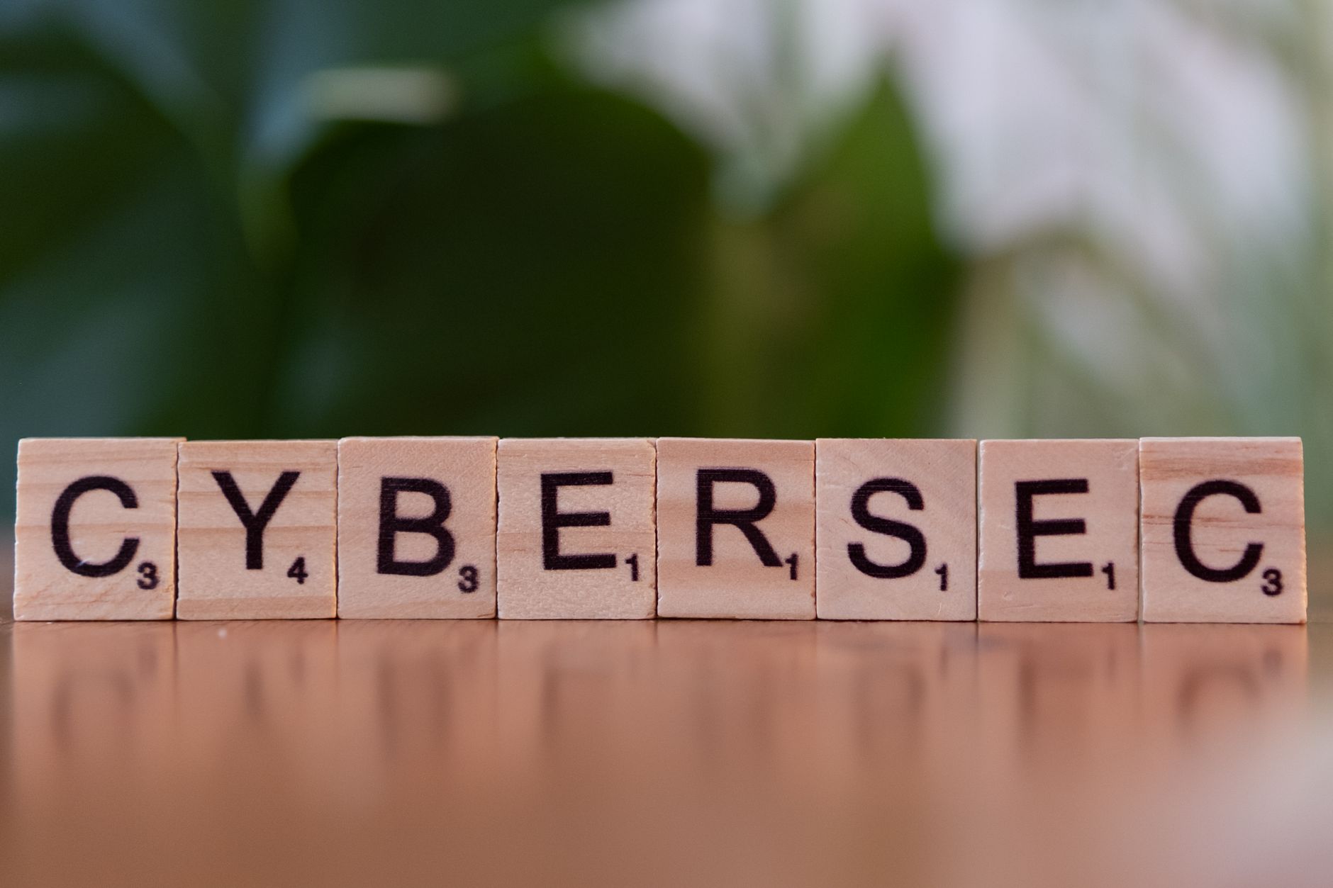 Drewniane klocki z napisem CYBERSEC na zielonym, rozmytym tle